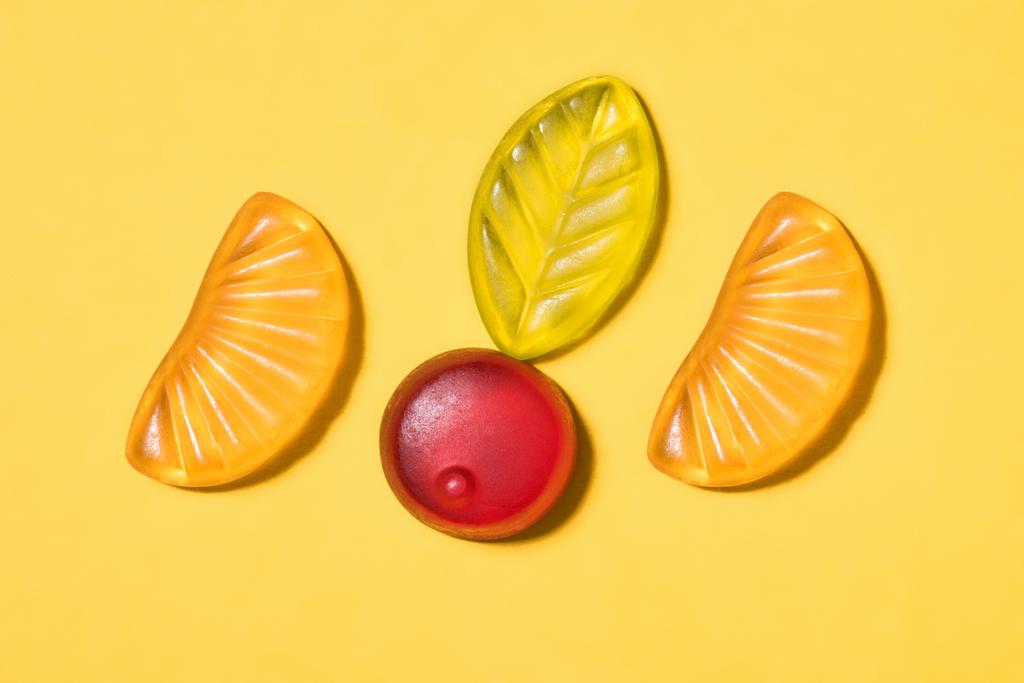 vista superior de sabrosos frutos gomosos en la superficie amarilla
 - Foto, imagen