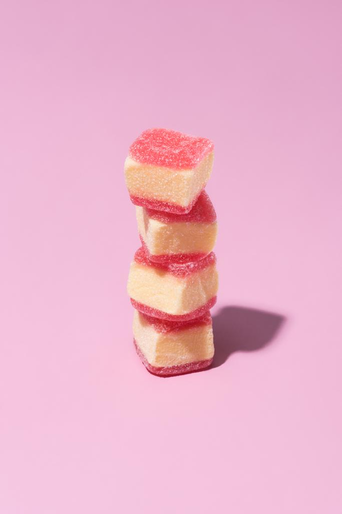 стопка солодких жувальних цукерок на рожевій поверхні
 - Фото, зображення