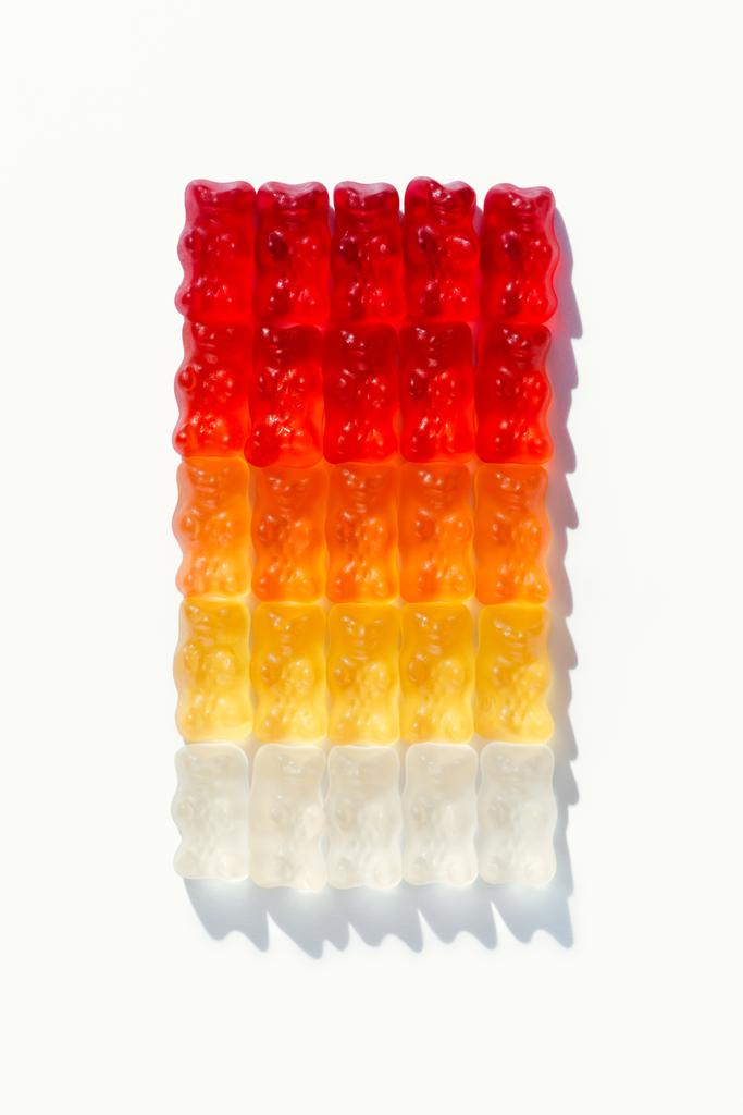 κάτοψη της σύνθεσης του gummy αρκούδες σε σχήμα ορθογωνίου ντεγκραντέ σε λευκό - Φωτογραφία, εικόνα