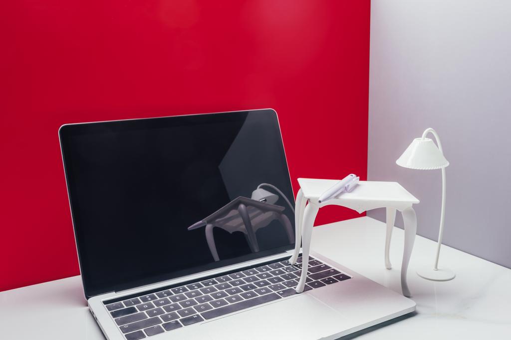 real size laptop with toy table and lamp in miniature red room - Photo, Image