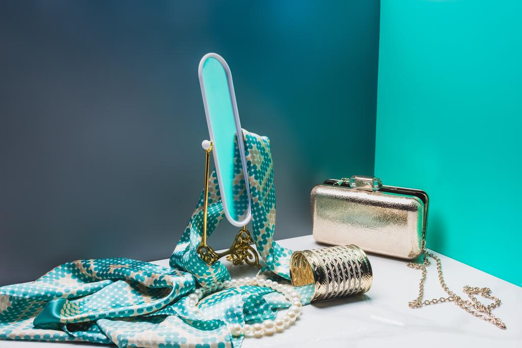 Spielzeugspiegel mit Seidentuch und weiblichen Accessoires im Miniaturblauen Raum - Foto, Bild