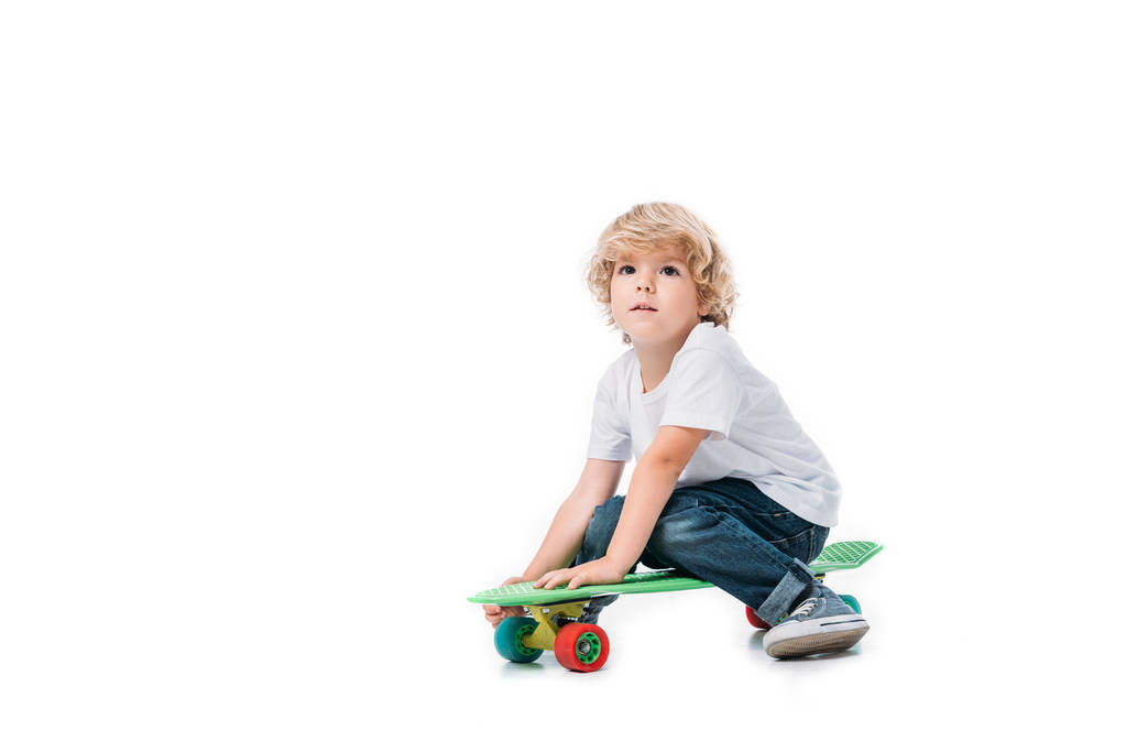 αξιολάτρευτο παιδί κάθεται στο skateboard που απομονώνονται σε λευκό - Φωτογραφία, εικόνα