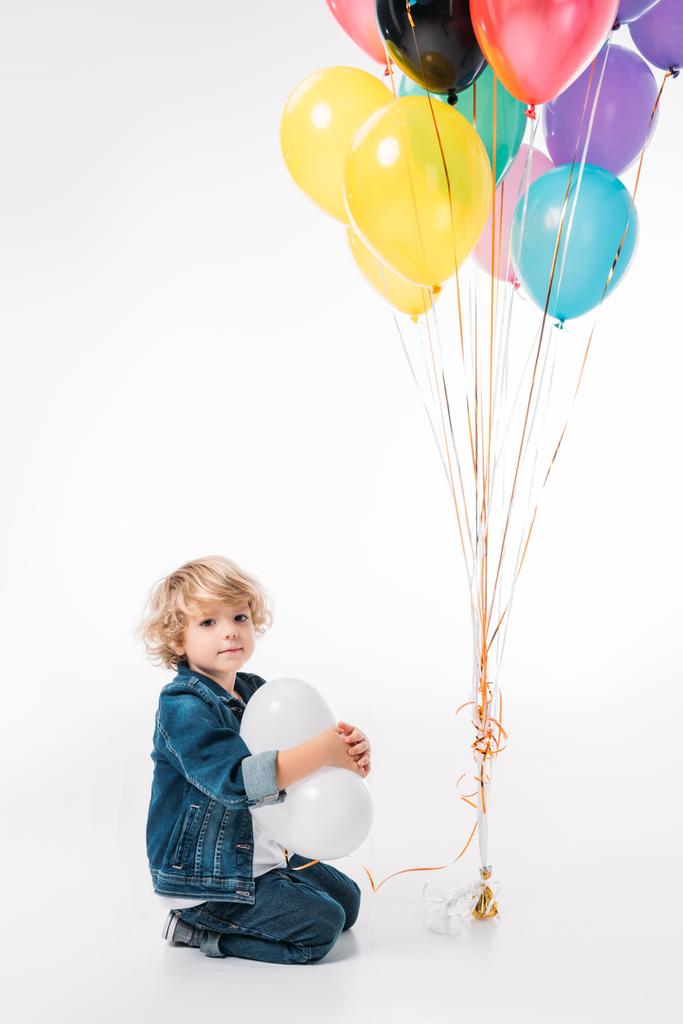 adorable boy sitting with bundle of balloons on white - Photo, Image