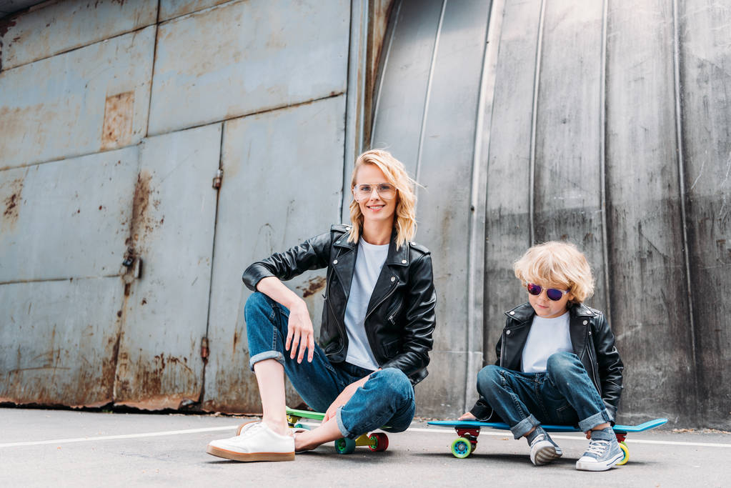 madre e figlio seduti su skateboard in strada
 - Foto, immagini