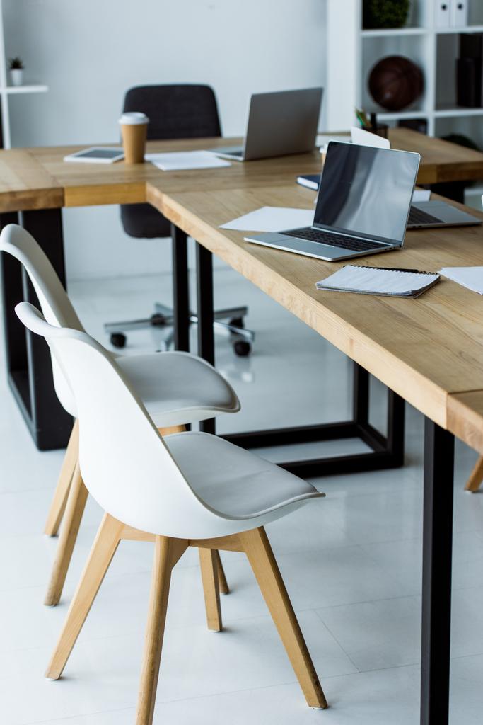 интерьер офиса с ноутбуками и кофе в бумажных стаканах на столах
 - Фото, изображение