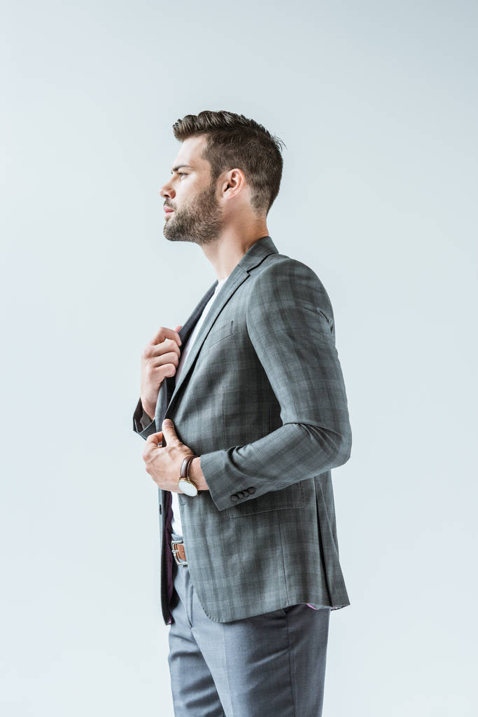 Homem de negócios confiante na moda endireitando seu terno isolado no fundo branco
 - Foto, Imagem