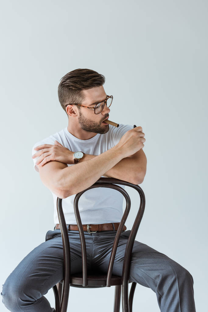 bello barbuto uomo accendendo il suo sigaro mentre seduto su sedia isolato su sfondo bianco
 - Foto, immagini