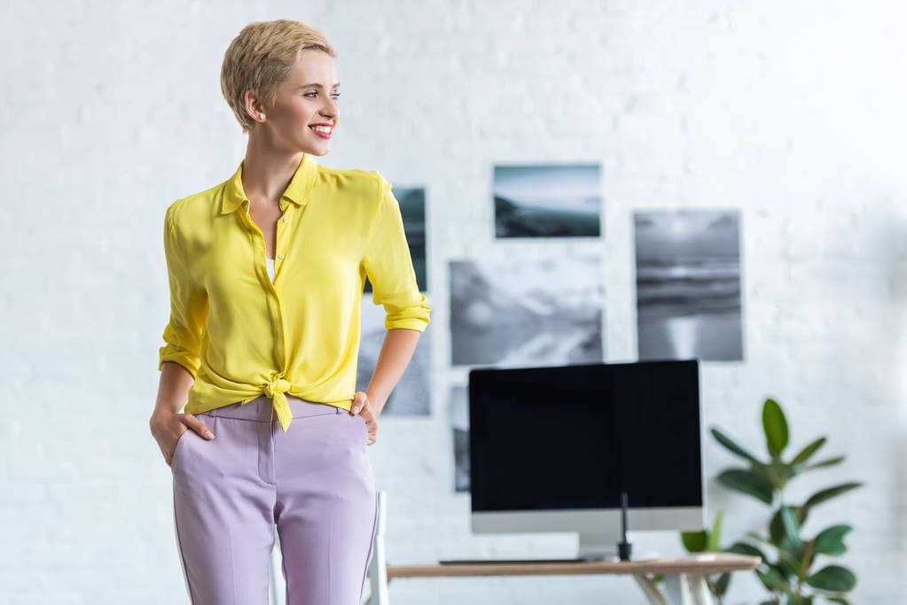 улыбающаяся деловая женщина с руками в карманах, смотрящая в сторону офиса
  - Фото, изображение