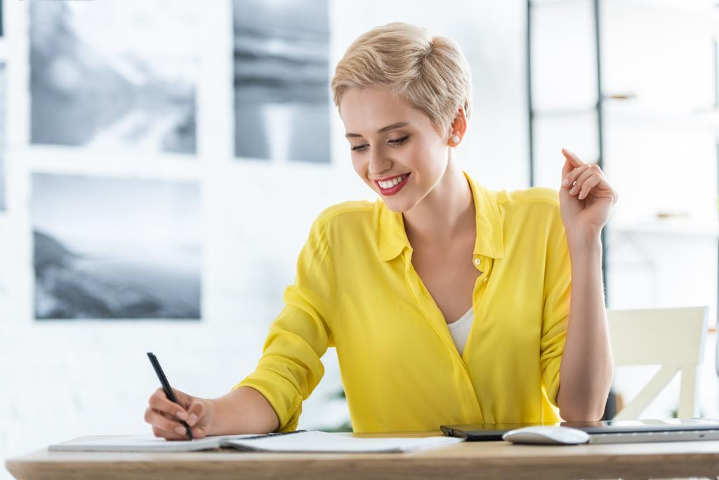 mosolygó női szabadúszó írásban tankönyv, asztal, grafikus digitalizáló tábla és a számítógép otthon office  - Fotó, kép