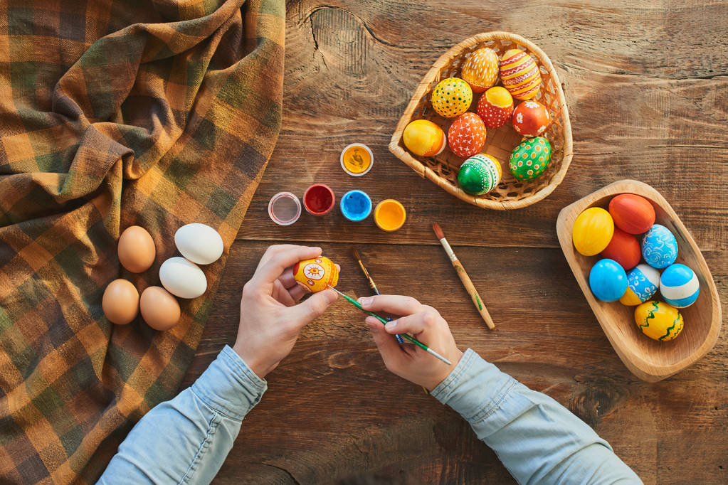 Frau bemalt buntes Ei für Osterurlaub zu Hause  - Foto, Bild