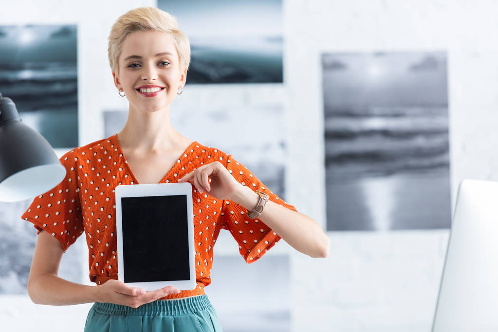 Lächelnde Frau präsentiert digitales Tablet mit leerem Bildschirm  - Foto, Bild