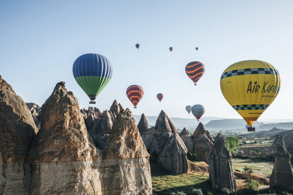 CAPPADOCIA, TURKEY - 09 MAY, 2018: hot air balloons flying in sky above majestic rock formations in famous cappadocia, turkey     - Photo, Image