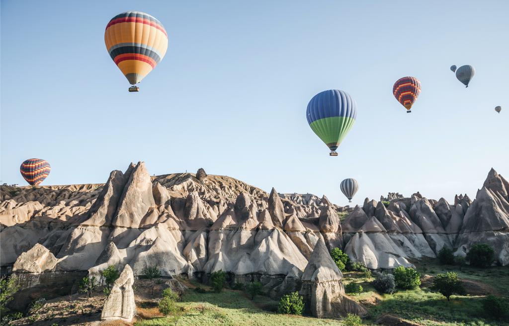 CAPPADOCIA, TURKEY - 09 MAY, 2018: colorful hot air balloons flying in sky above beautiful rock formations in cappadocia, turkey   - Photo, Image