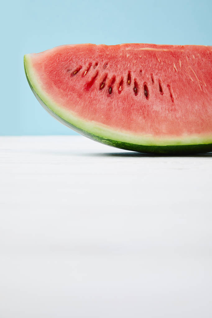 close up view of fresh watermelon slice on white surface on blue background - Photo, Image