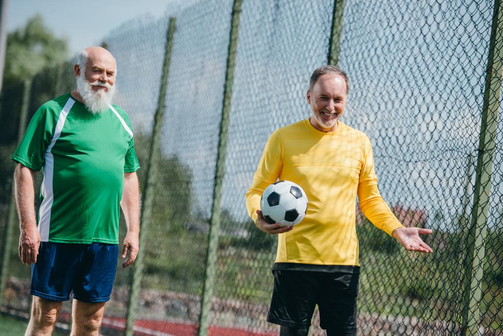 Portret van oude mannen in pak met voetbal bal op veld voetbal glimlachen - Foto, afbeelding