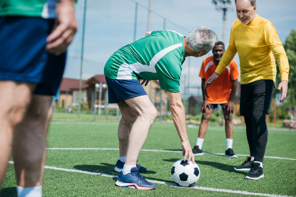 partial view of multicultural elderly friends playing football together - Photo, Image