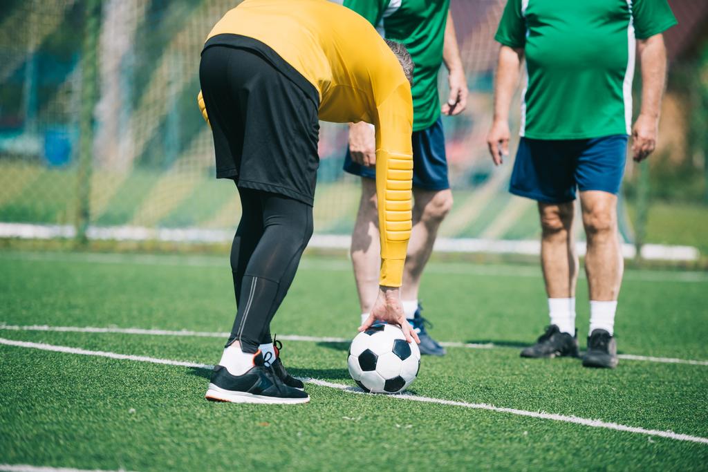 Teilansicht alter Männer, die gemeinsam auf dem Feld Fußball spielen - Foto, Bild