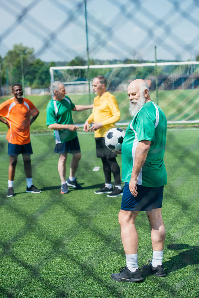 selectieve aandacht multiraciale oude vrienden met voetbal bal op groene veld - Foto, afbeelding
