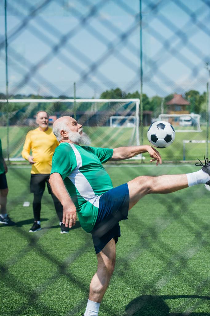 частичный взгляд пожилых мужчин, играющих в футбол на поле
 - Фото, изображение