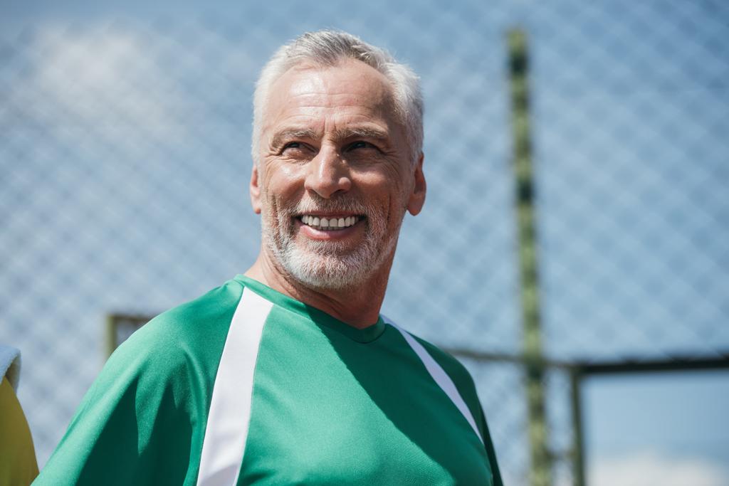 πορτρέτο του χαμογελώντας ηλικιωμένος άνδρας στα αθλητικά βλέπει μακριά - Φωτογραφία, εικόνα