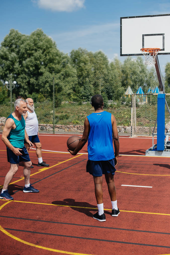 багаторасові літні чоловіки грають у баскетбол разом на ігровому майданчику в літній день
 - Фото, зображення