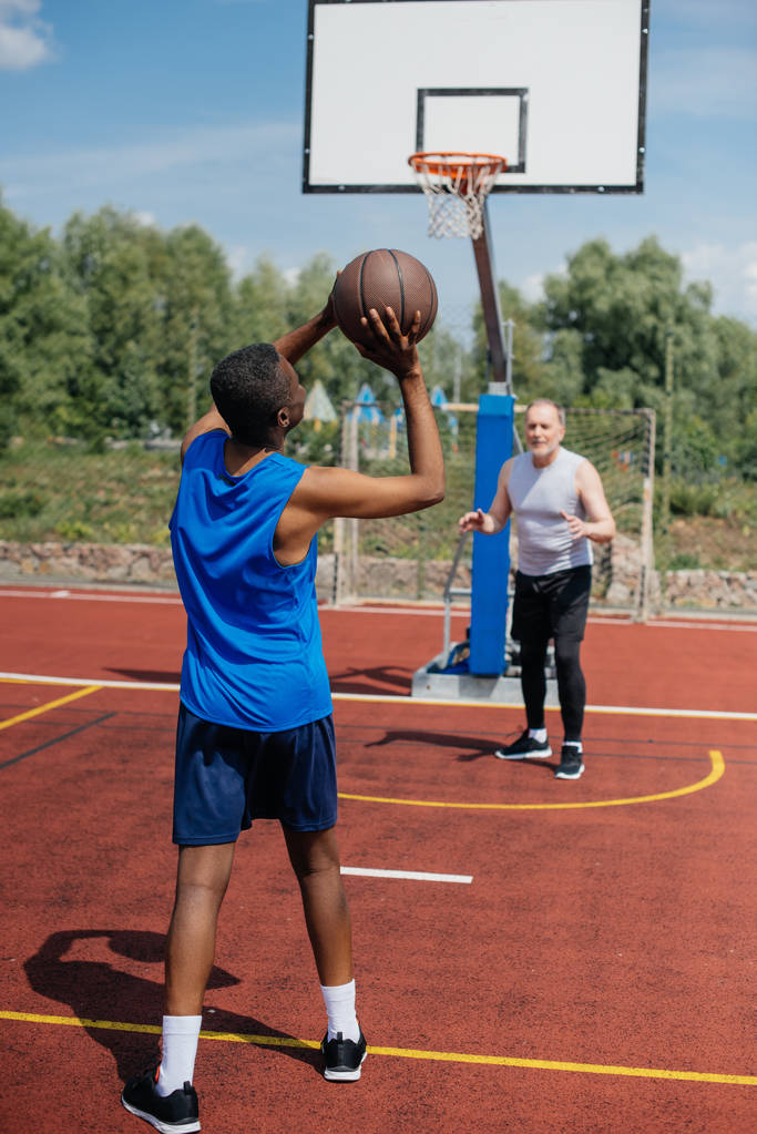 Senioren spielen an Sommertagen gemeinsam Basketball auf Spielplatz - Foto, Bild