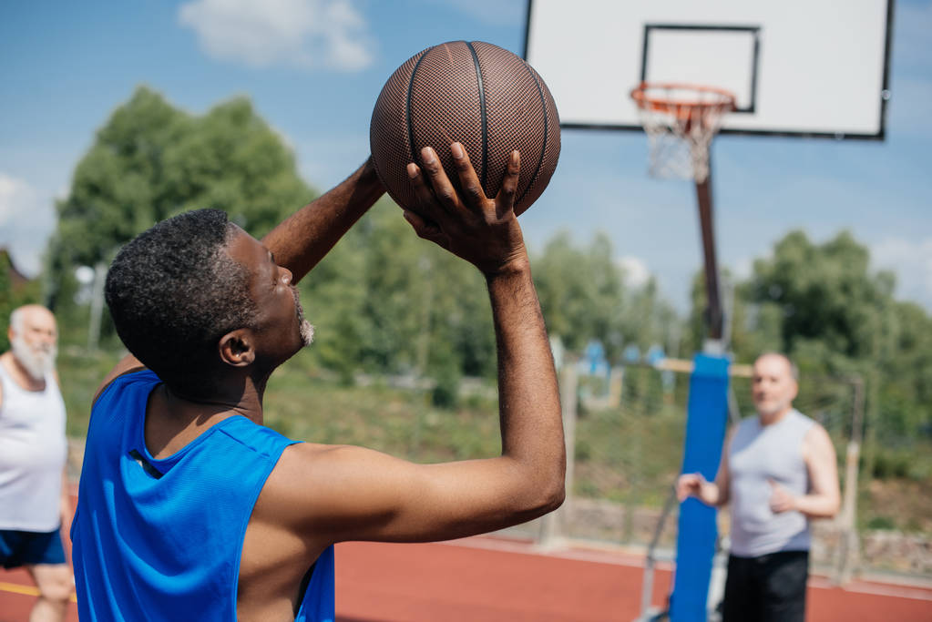 mnohonárodnostní starších mužů společně hrát basketbal na hřišti v letním dni - Fotografie, Obrázek