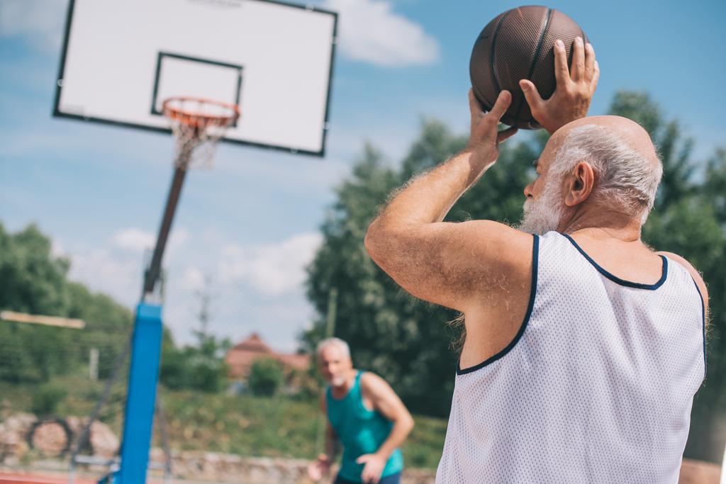 hombres mayores jugando baloncesto juntos en el patio de recreo en el día de verano
 - Foto, imagen