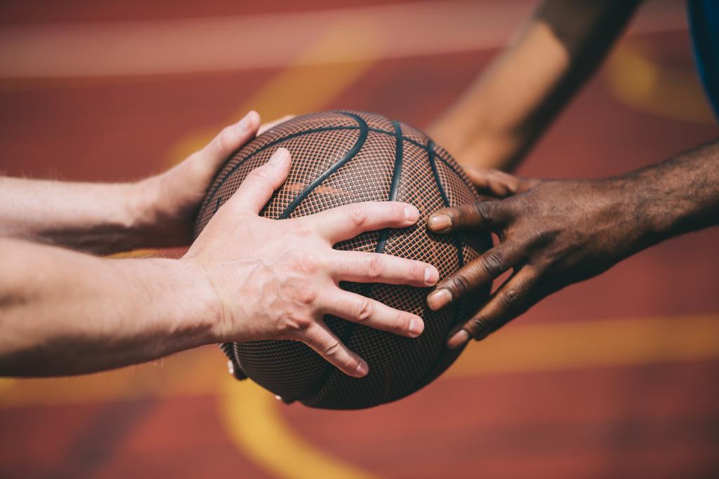 vista parcial del hombre dando pelota de baloncesto a viejo amigo afroamericano
 - Foto, imagen
