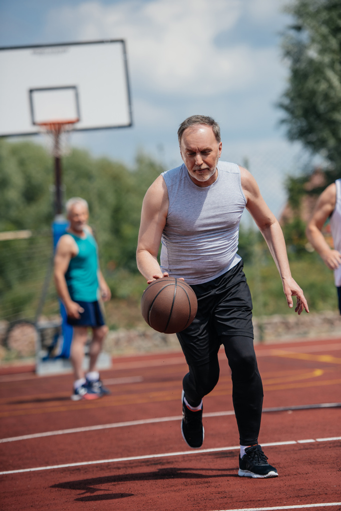 valikoiva painopiste vanhoja ystäviä pelaa koripalloa kesäpäivänä
 - Valokuva, kuva