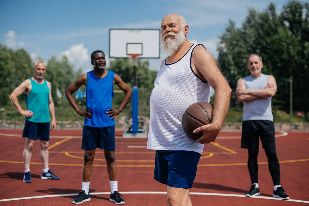 foco seletivo de atletas idosos multiétnicos com bola de basquete no playground
 - Foto, Imagem