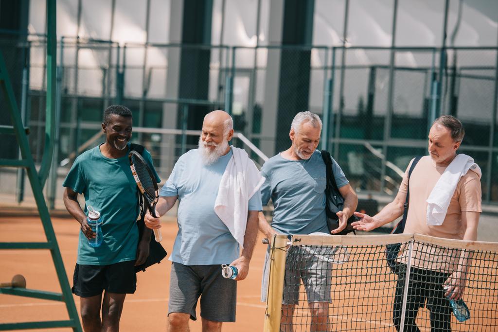 Portrait lächelnder älterer Freunde mit Tennisausrüstung auf dem Platz - Foto, Bild