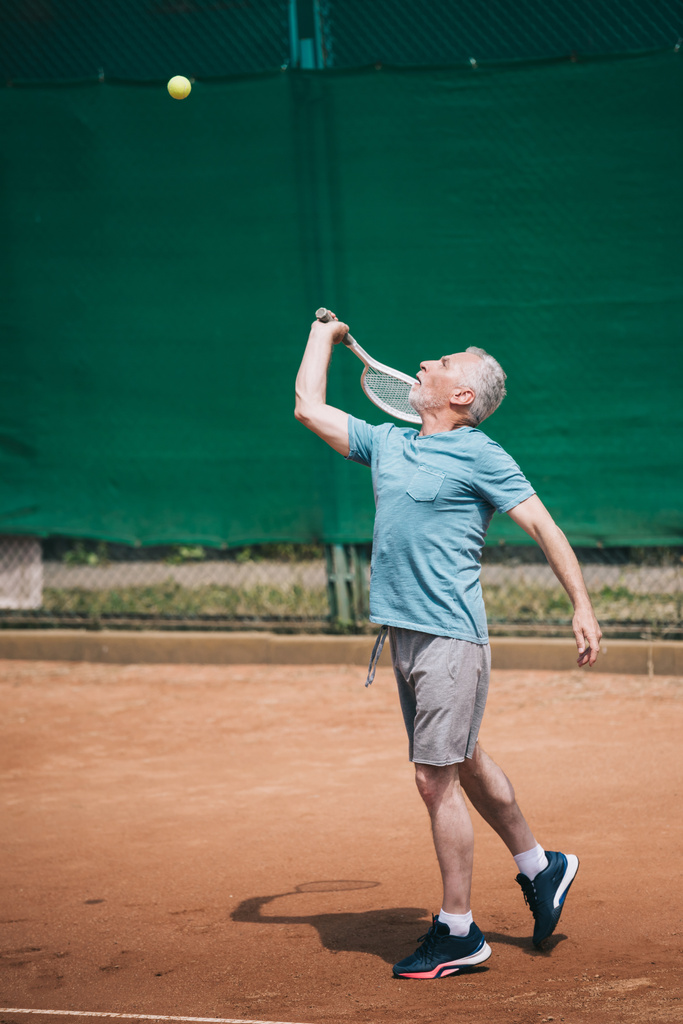 old man playing tennis on court on summer day - Photo, Image
