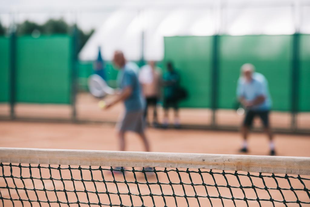 selective focus of net and tennis players playing tennis on court - Photo, Image