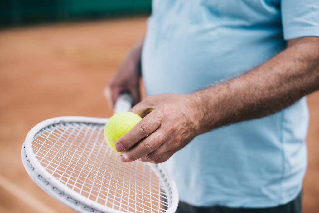 partial view of old man with tennis equipment in hands - Photo, Image
