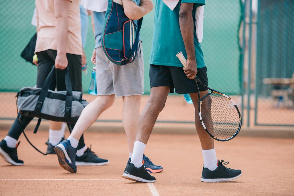 częściowy widok wielokulturowym starszych mężczyzn z chodzenia na korcie do tenisa - Zdjęcie, obraz