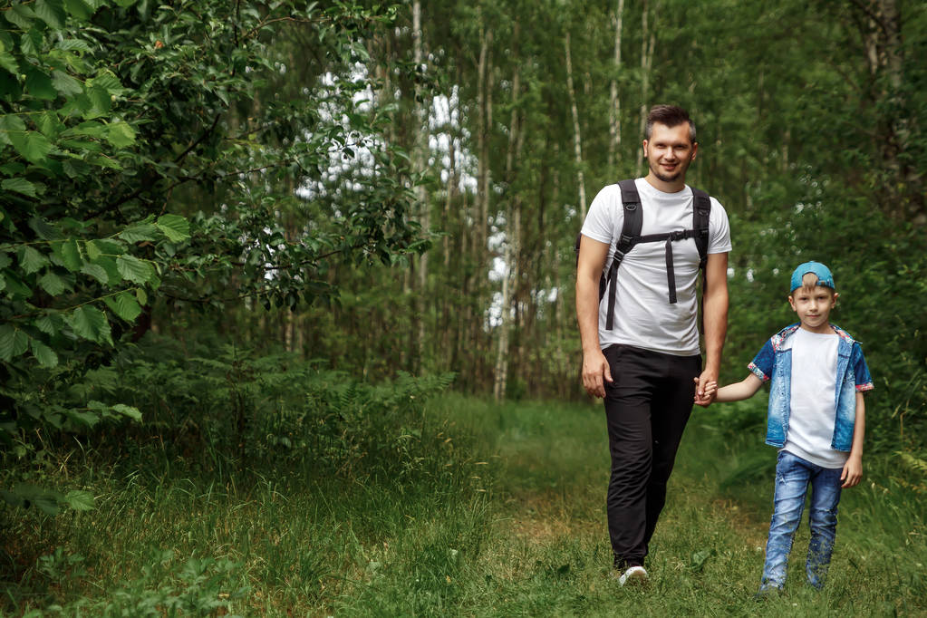Человек с рюкзаком, отец с сыном в походе, гуляющий по лесу. Семейная жизнь, времяпрепровождение с семьей, воспитание детей
. - Фото, изображение