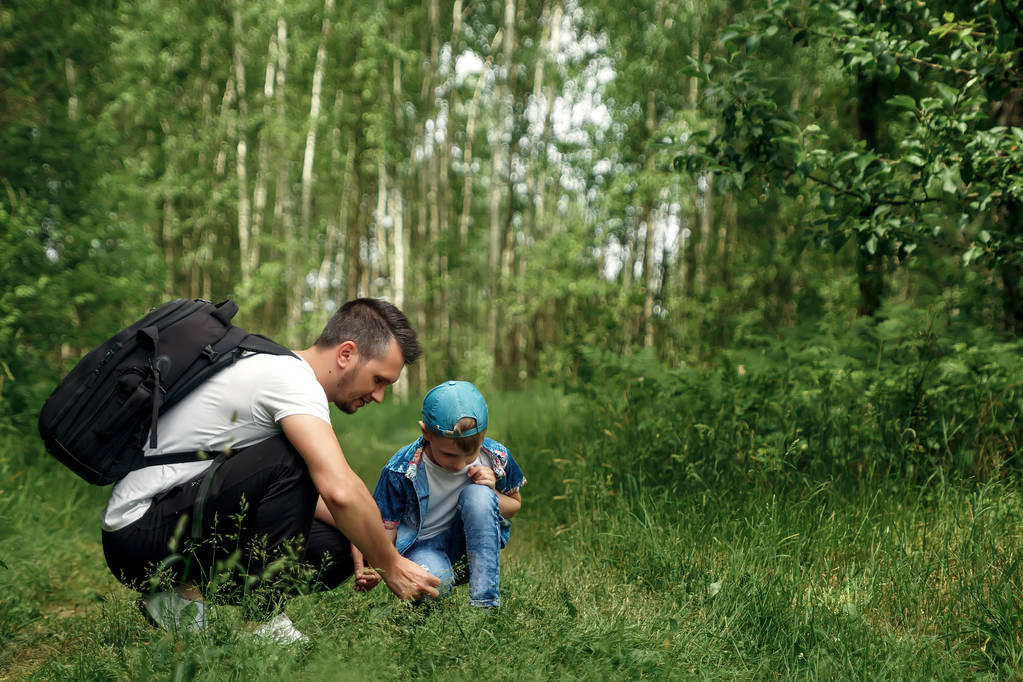 Een man met een rugzak, een vader en zijn zoon op een wandeling, wandelen tijdens wandelingen in het bos. Gezinsleven, tijdverdrijf met het gezin, de opvoeding van kinderen. - Foto, afbeelding