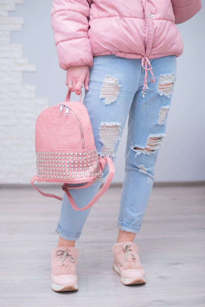 Outfit der lässigen Frau. Jeans, Lederrucksack, rosa Turnschuhe auf grauem Hintergrund. Mädchenlook - Foto, Bild