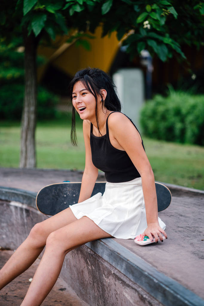 Πορτρέτο της Ασίας κινεζική κορίτσι με κινητό τηλέφωνο και skate στο skatepark - Φωτογραφία, εικόνα