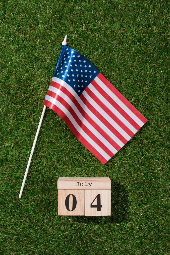 top view of american flagpole and wooden calendar with 4th july date on green grass, americas independence day concept - Photo, Image