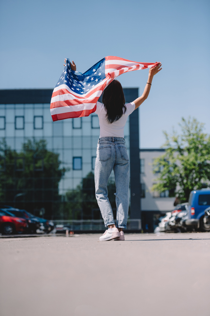 back view of woman with American flag in hands standing on street, 4 heinäkuu loma käsite
 - Valokuva, kuva