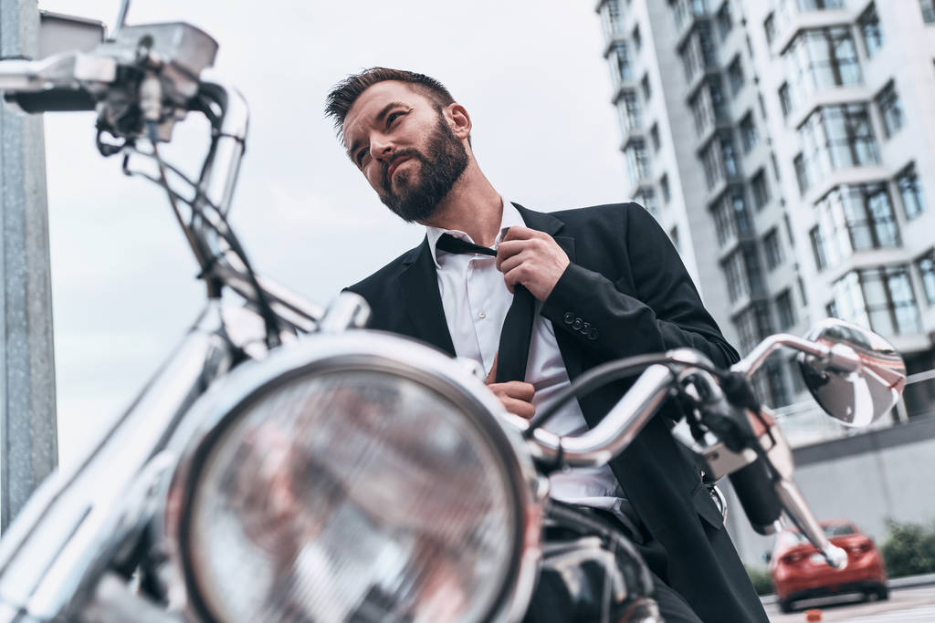 beau jeune homme d'affaires ajuster cravate tout en étant assis sur la moto
 - Photo, image