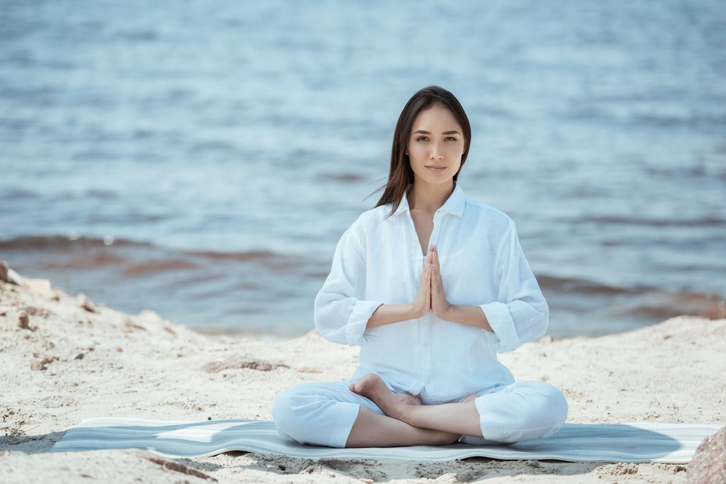 giovane donna asiatica in anjali mudra (sigillo di saluto) posa sul tappetino yoga via mare
  - Foto, immagini