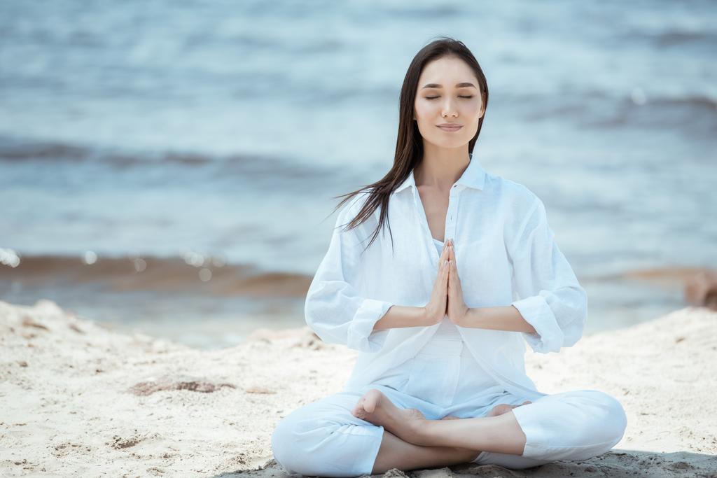 attractive young asian woman in anjali mudra (salutation seal) pose on beach - Photo, Image