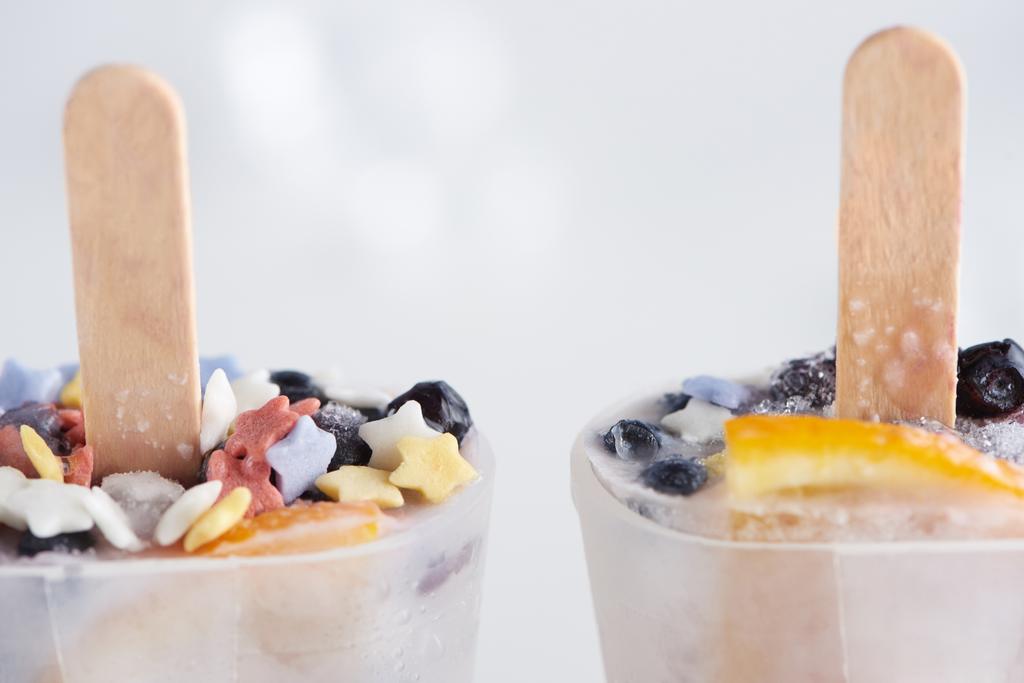 close-up view of sweet homemade ice cream with sticks in containers on grey    - Photo, Image