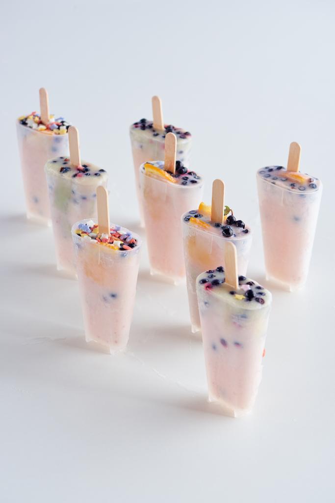 вкусные домашние фруктовые мороженое с палочками в контейнерах на сером
  - Фото, изображение