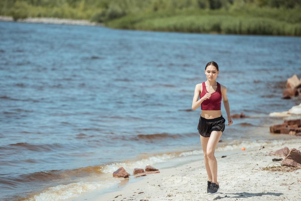 edessä näkymä nuori aasialainen nainen lenkkeilijä käynnissä rannalla
  - Valokuva, kuva