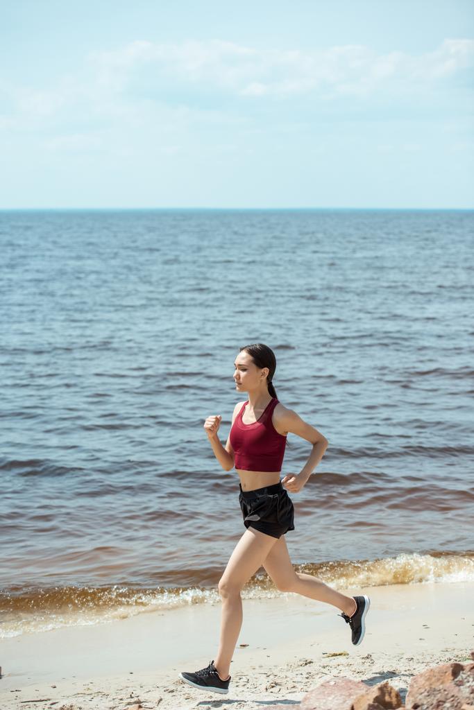 attractive young asian female jogger running on beach  - Photo, Image