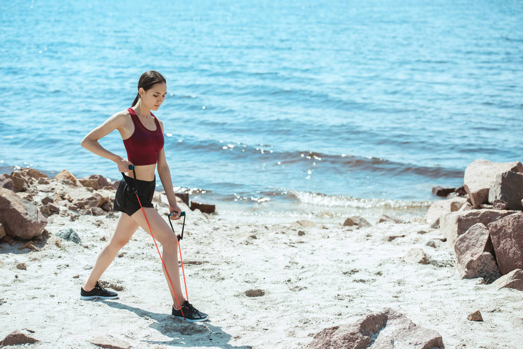 молодая спортсменка делает упражнения с растяжкой на пляже
  - Фото, изображение
